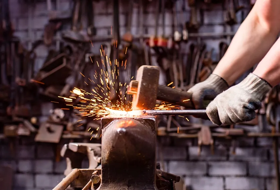 A blacksmith striking hot steel at the forge